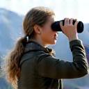 Porträt von Sophia aus Berlin, mit einem Fernglas, beobachtet Wildtiere am Berghang.